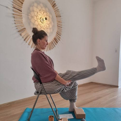 Frau sitzt auf einem Sessel praktiziert Yoga mit einem Gurt